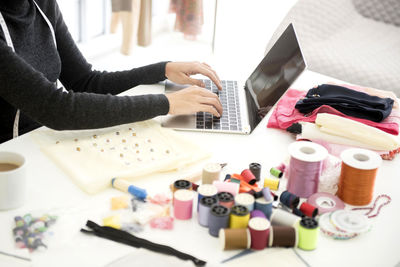 Midsection of woman using laptop on table