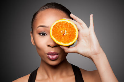 Close-up of woman holding apple against black background