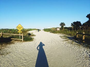 Shadow of man on road against clear sky