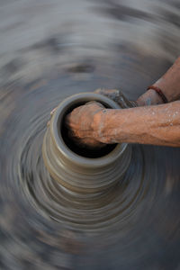 Hands working on pottery wheel and making a pot