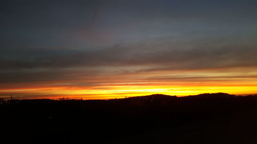 Silhouette landscape against dramatic sky during sunset