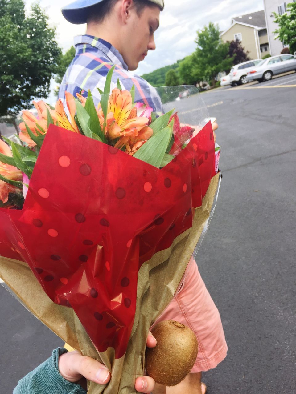 one person, real people, holding, outdoors, lifestyles, leisure activity, casual clothing, day, flower, standing, road, freshness, men, bouquet, human hand, human body part, tree, flower head, close-up, young adult, people