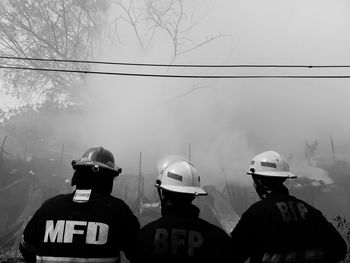 Rear view of people standing on foggy weather