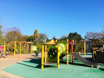 Playground in park against clear blue sky