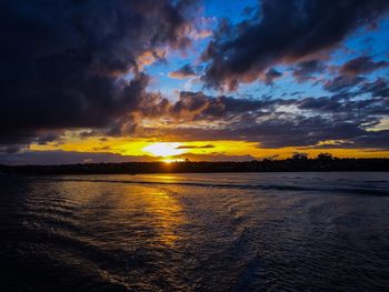 Scenic view of sea against cloudy sky during sunset