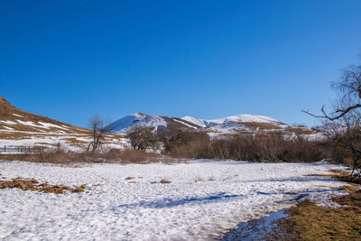 Scenic view of snowcapped mountains against clear blue sky