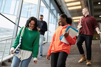 Low angle view of happy university students walking down on steps