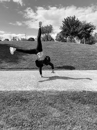 Full length of woman practicing handstand on footpath in park