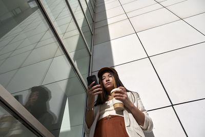 Low angle view of woman standing on mobile phone