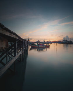 Pier over lake against sky during sunset