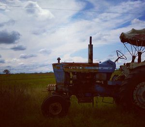 View of field against cloudy sky