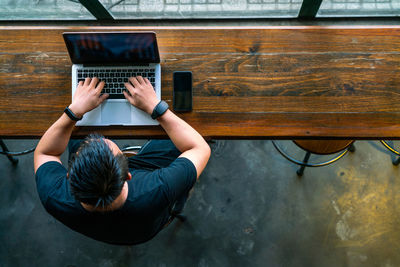 Rear view of woman using laptop on table