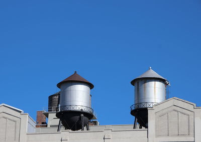 Low angle view of water tower against clear blue sky