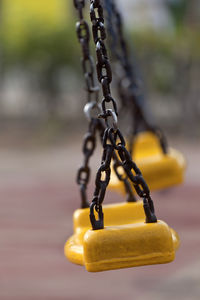 Close-up of empty swings hanging in playground