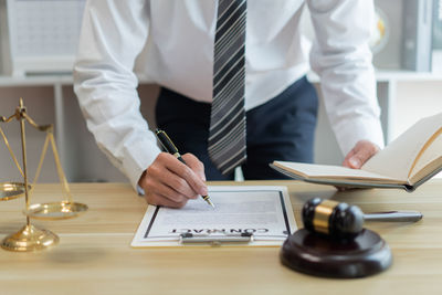 Midsection of lawyer working at desk in office