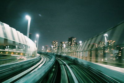 Illuminated railroad tracks in city at night