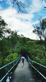 Man on footbridge against sky