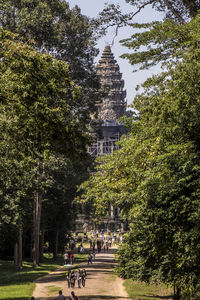 People outside temple amidst trees and building