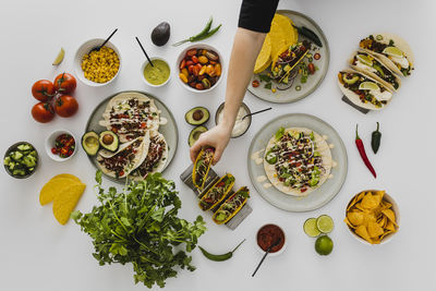 Person preparing healthy feast with various mexican food