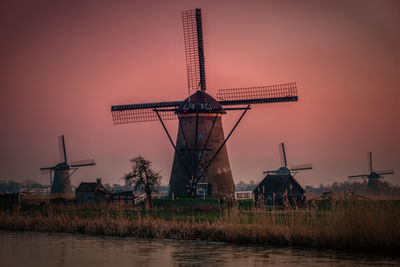 Traditional windmill on field during sunset