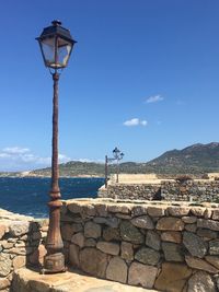 Street light by sea against blue sky