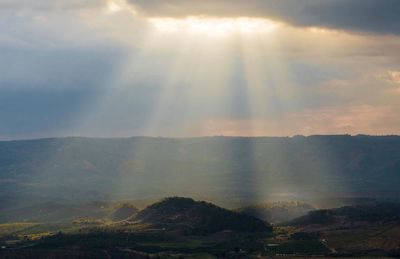 Sunlight streaming through clouds over mountain