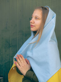 Portrait of young woman standing against wall