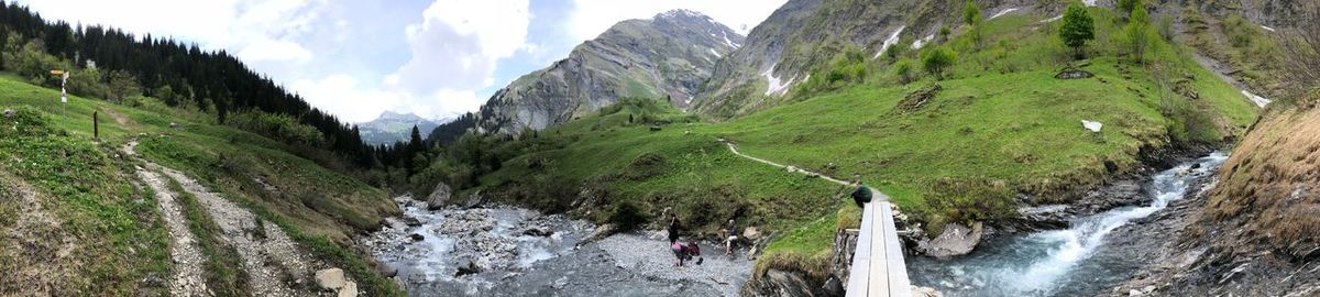 Panoramic view of people walking on mountain against sky