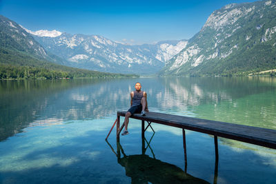 Front view of man sitting by lake