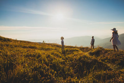 People standing on field against bright sun