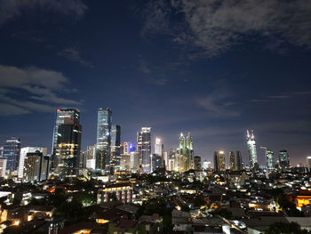 Illuminated buildings in city against sky at night