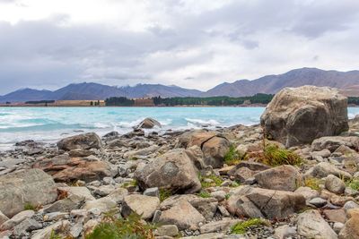 Rocks on shore by sea against sky