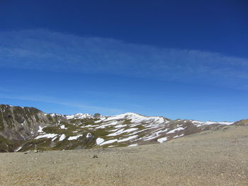 Scenic view of snow covered mountains against blue sky