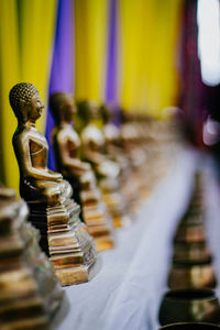 Golden buddha statues arranged on shelf at temple