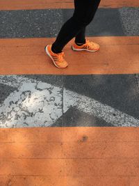 Low section of woman wearing orange shoes walking on road