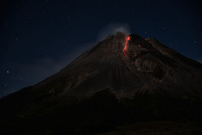Low angle view of volcanic mountain against sky at night