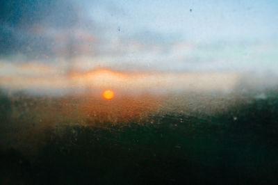 Raindrops on glass window during sunset