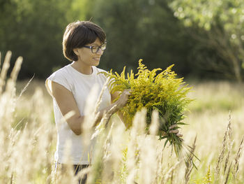 Young woman standing against plants