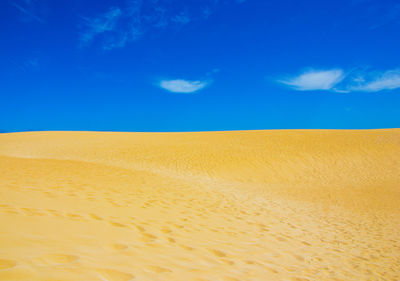 Scenic view of sand dunes against blue sky