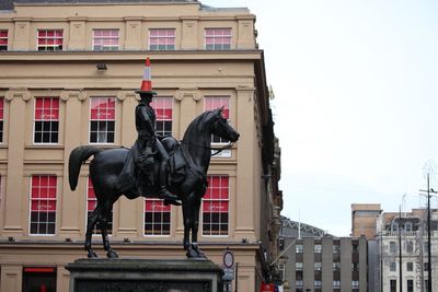 Statue of horse in city against sky