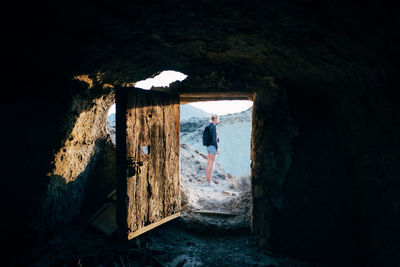 Woman standing on mountain seen through doorway