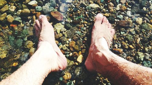 Low section of man on pebbles at beach