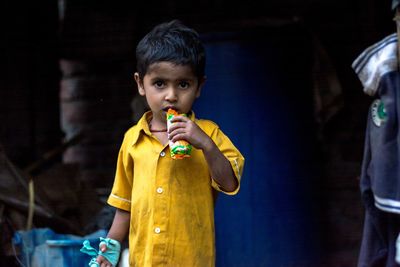 Portrait of boy eating food while standing outdoors
