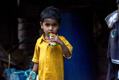 Portrait of boy eating food while standing outdoors