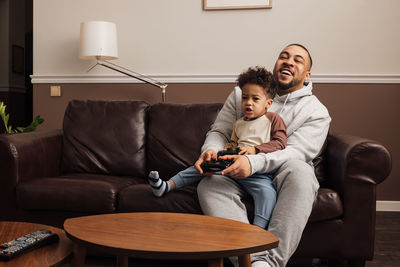 Cheerful father and son playing game at home