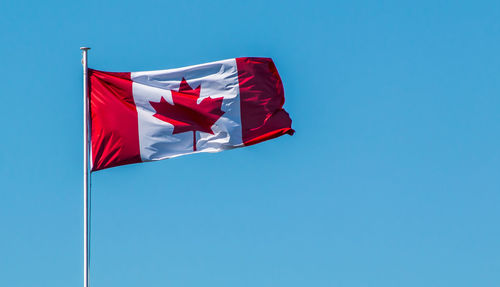 Low angle view of american flag against clear blue sky