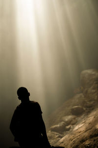 Rear view of silhouette man standing on rock