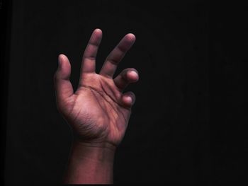 Close-up of human hand over black background