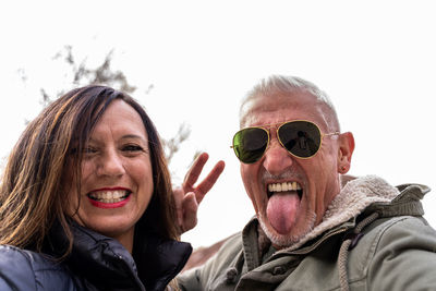 Happy middle aged couple taking a selfie showing victory sign in a public park