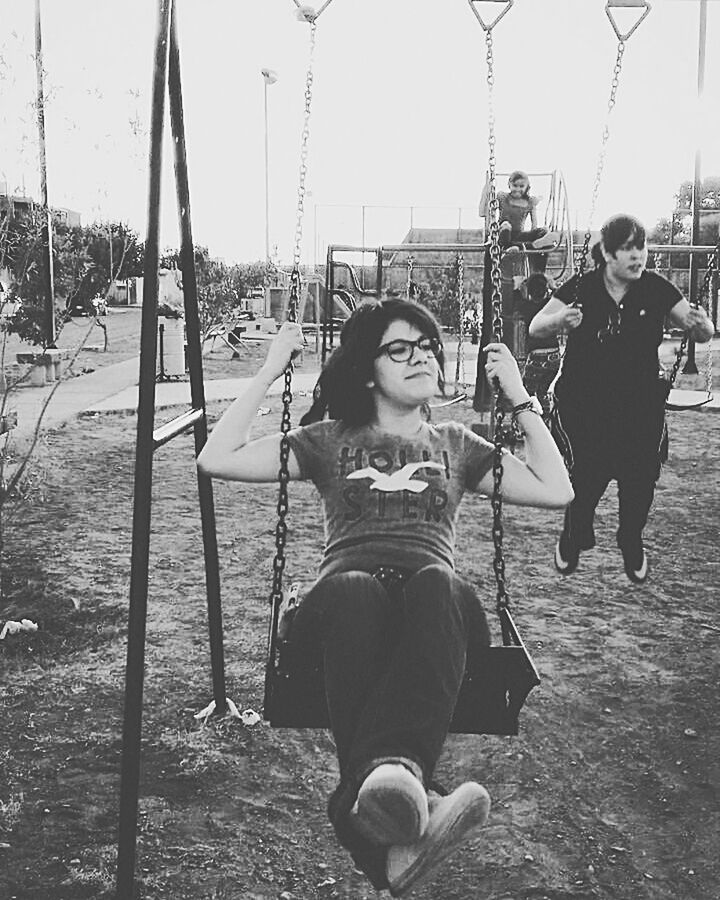 lifestyles, leisure activity, casual clothing, full length, person, childhood, sunlight, standing, transportation, day, sitting, enjoyment, swing, fun, outdoors, girls, incidental people